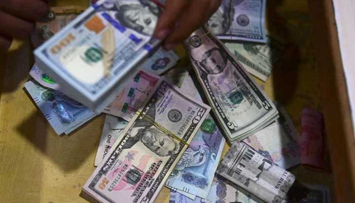 A dealer collect US dollars at a money exchange market in Karachi on January 26, 2023. — AFP