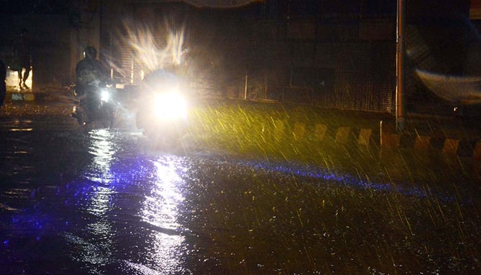 Motorcyclists ride through heavy rain in Karachi, on March 18, 2026. — APP