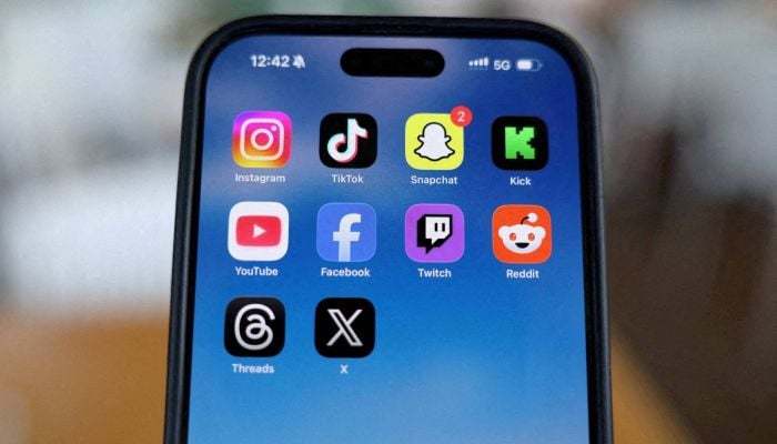 Instagram, TikTok, Snapchat, Kick, YouTube, Facebook, Twitch, Reddit, Threads and X applications are displayed on a mobile phone. — Reuters