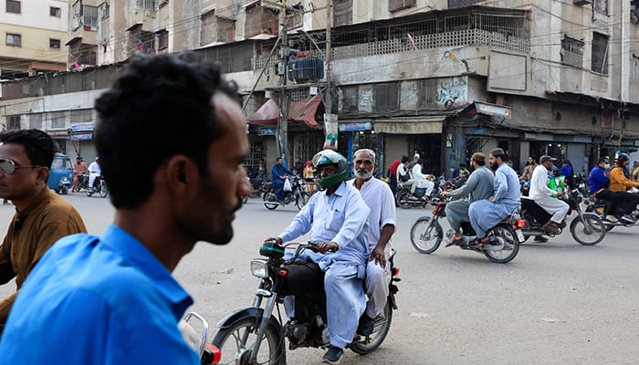 A rider offering ride and parcel delivery services rides with a customer to drop him at his destination in Karachi, March 17, 2026. — Reuters