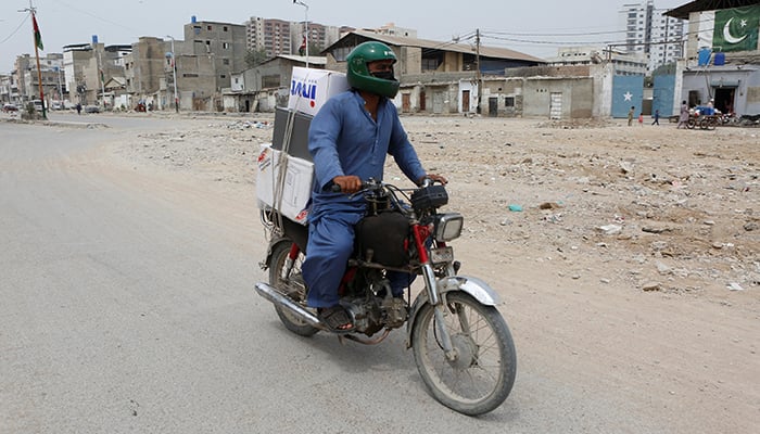 Malik Mohsin Ali, a rider, ride-hailing and delivery platform, heads to deliver parcels in Karachi, March 18, 2026. — Reuters