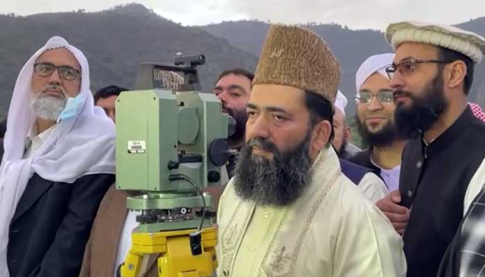 Central Ruet-e-Hilal Committee Chairman Maulana Abdul Khabeer Azad, surrounded by religious scholars and clerics, looks in the telescope to spot the crescent moon in Islamabad on March 19, 2026. — Screengrab via Geo News