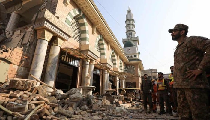 A soldier and rescue workers survey the damage after a suicide blast in a mosque in Peshawar. — Reuters