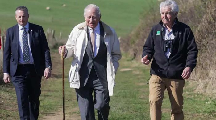 King Charles treks England Coast Path with walking stick