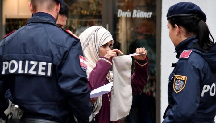 Police officers ask a woman to unveil her face in Zell am See, Austria, on October 1, 2017. — AFP