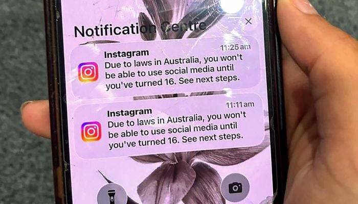 A teenager holds a phone displaying a message from social media platform Instagram after the account was locked for age verification in Australia. — AFP
