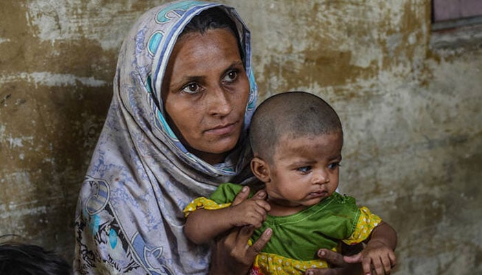 Sabira Rashid, a Pakistani woman, holds her child as she speaks during an interview with AFP at their house in Baba Island along the Karachi Harbour in Karachi in this photograph taken on June 6, 2024. — AFP