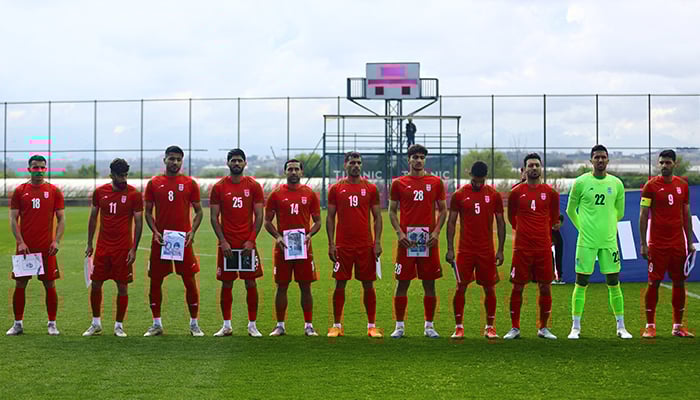 Iran players hold pictures of damaged buildings and young victims as they line up before the friendly match against Costa Rica at Mardan Sports Complex, Antalya, Turkiye, March 31, 2026. — Reuters