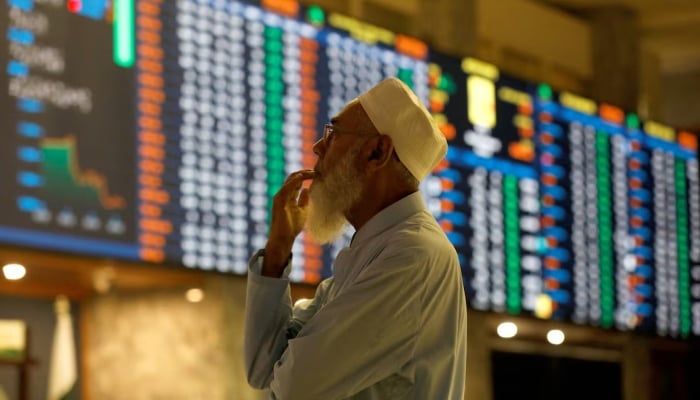 A stockbroker reacts while monitoring the market on the electronic board displaying share prices during a trading session at the Pakistan Stock Exchange, in Karachi, July 3, 2023. — Reuters