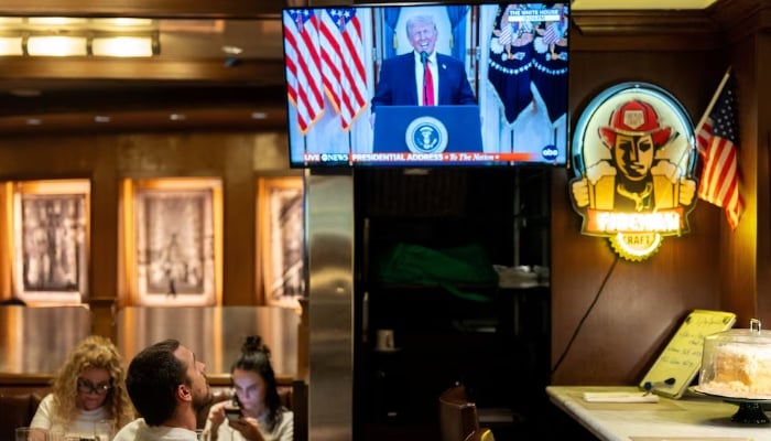A customer watches U.S. President Donald Trump address the nation on the Iran crisis from the White House in Washington, DC, on screen at Brooklyn Diner in Times Square, New York, US, April 1, 2026. — Reuters