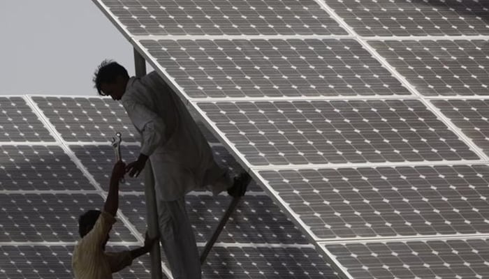 Technicians work on a solar panel at a power station near Karachi June 18, 2010. — Reuters