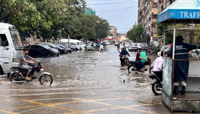 A traffic police officer manages the flow of vehicles as commuters navigate a waterlogged road following heavy rainfall in Karachi on April 2, 2026. — Geo.tv