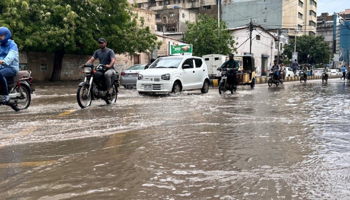Commuters make their way through accumulated water after heavy rainfall in Karachi on April 2, 2026. — Geo.tv