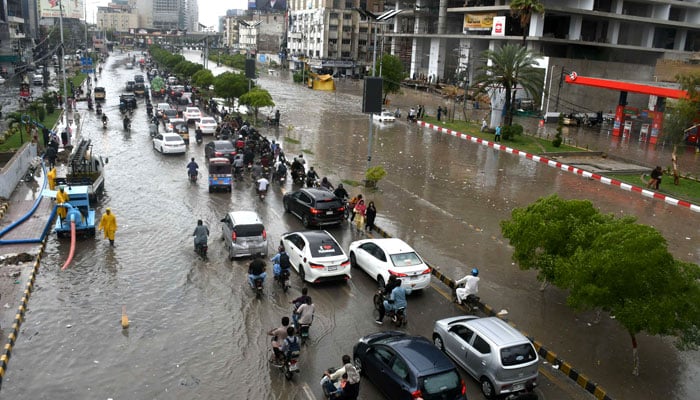 Commuters wade through floodwater after heavy rainfall in Karachi on April 2, 2026. — Online
