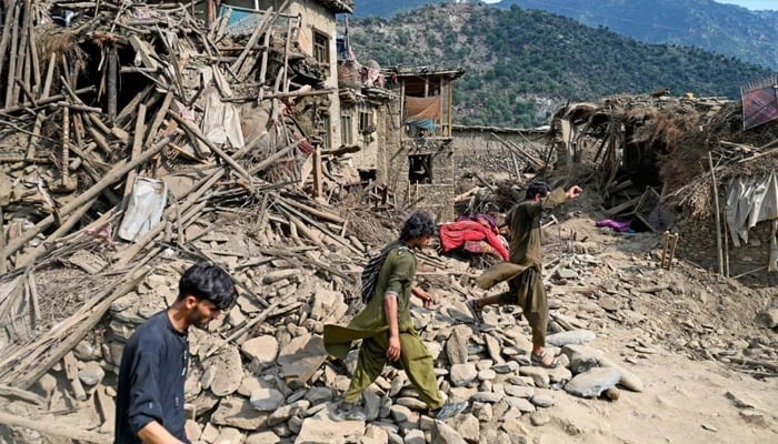 People passing by the destroyed house in Afghanistan. —AFP/File