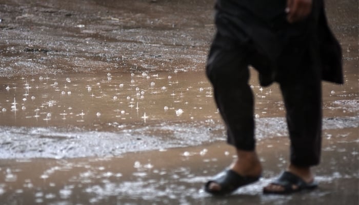 A man walks on a road during heavy rain in morning hours in Rawalpindi, March 30, 2026. — Online