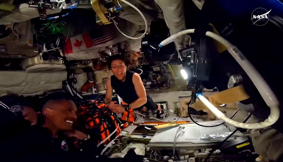 This screengrab from a Nasa live broadcast video footage shows Nasa astronaut and Artemis II Mission Specialist Christina Koch (R) and Nasa astronaut and Artemis II pilot Victor Glover working indside the Orion spacecraft as they pass the halfway point between Earth and the moon on the way to their planned lunar flyby in the Orion spacecraft, on April 3, 2026. — AFP