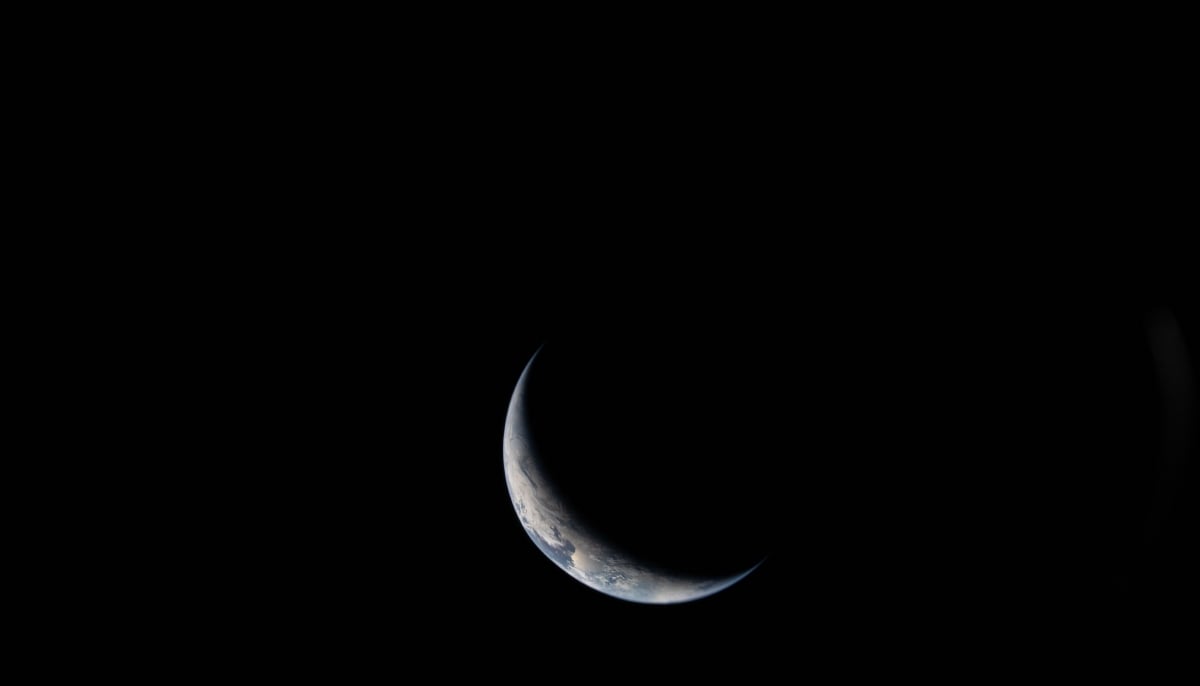 This handout picture provided by Nasa shows a sliver of Earth illuminated against the blackness of space taken by an Artemis II crew member through an Orion spacecraft window on April 3, 2026. — AFP