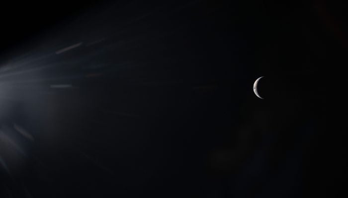 This handout picture by an Artemis II crew member provided by NASA shows an illuminated sliver of Earth set against the blackness of space through the window of the Orion spacecraft on April 3, 2026. — AFP