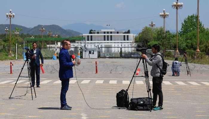 Members of the media report with the President house building in the background, as Pakistan prepares to host the US and Iran for peace talks, in Islamabad, April 10, 2026. — Reuters