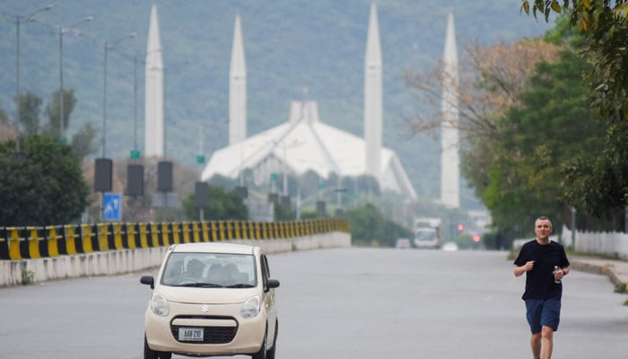 A man jogs along a road early in the morning near the Faisal Masjid, as delegations from the United States and Iran are expected to hold peace talks in Islamabad, Pakistan, April 11, 2026. — Reuters