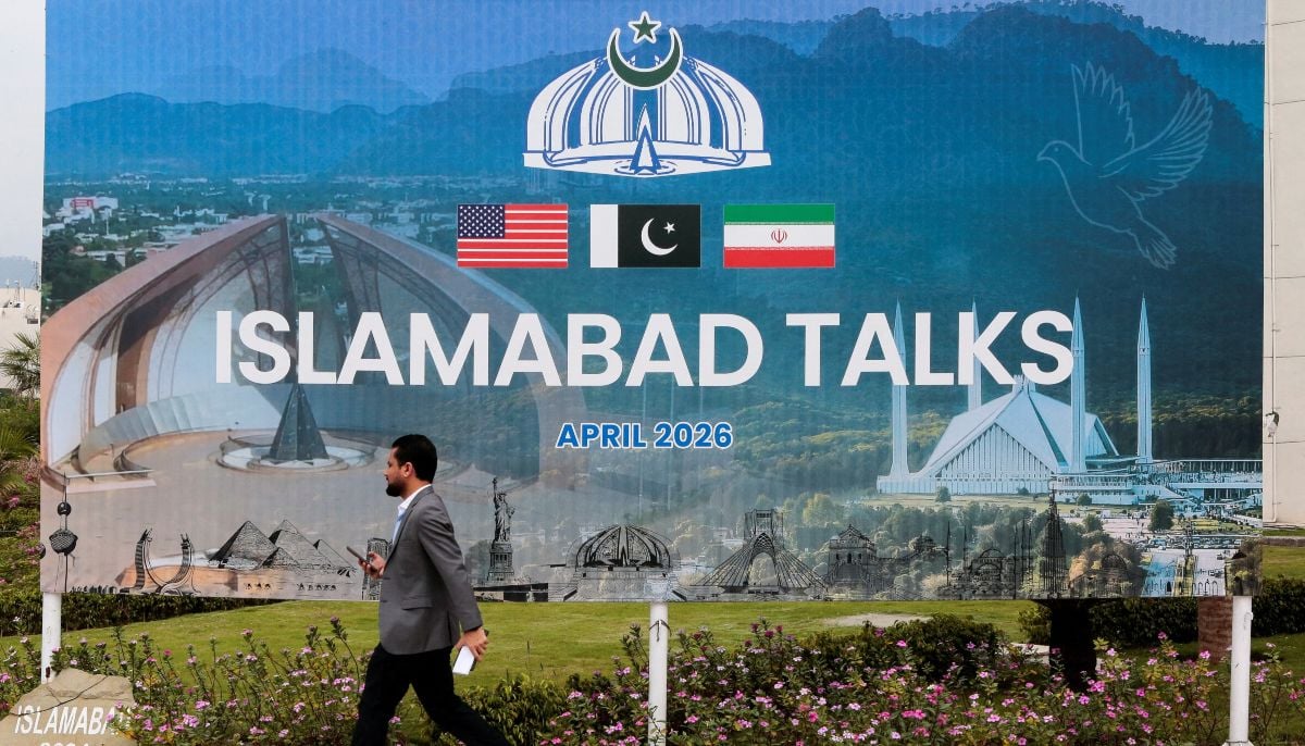 A man walks past a billboard near the media centre as delegations from the United States and Iran are expected to hold peace talks in Islamabad, April 11, 2026. — Reuters