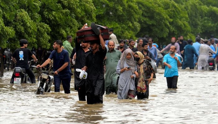 People wade through a flooded road after the monsoon rain in Karachi, August 19, 2025. — Reuters