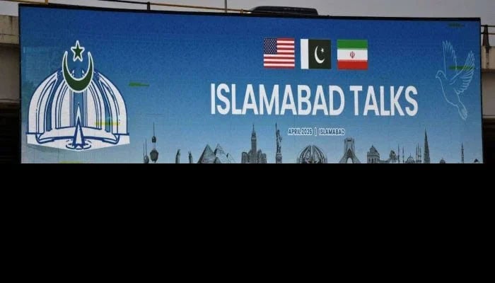 A man rides his motorbike past a billboard installed alongside a road as delegations from the United States and Iran are expected to hold peace talks in Islamabad, April 11, 2026. — Reuters