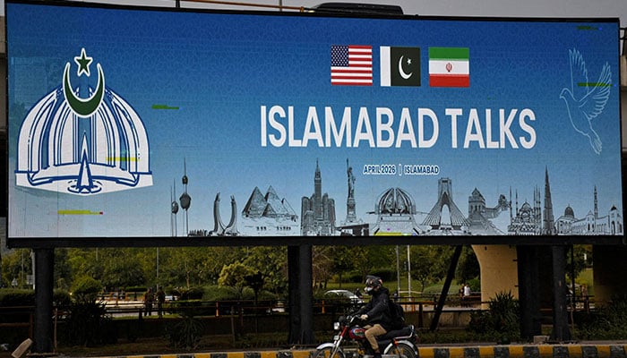 A man rides his motorbike past a billboard installed alongside a road as Pakistan prepares to host the US and Iran for peace talks, in Islamabad, Pakistan, April 10, 2026. — Reuters
