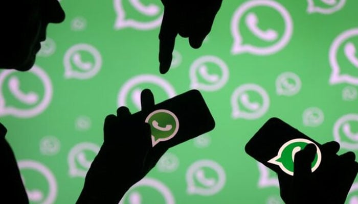 Men pose with smartphones in front of displayed Whatsapp logo in this illustration September 14, 2017. — Reuters