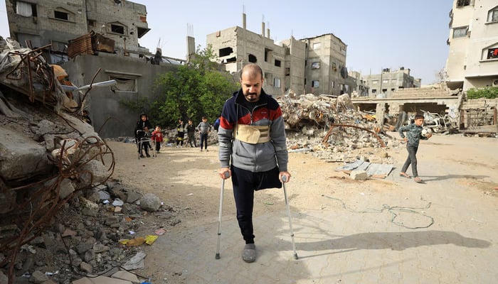 Palestinian amputee Hazem Foura, who lost one leg, walks using crutches in a street in Gaza City, April 3, 2026.