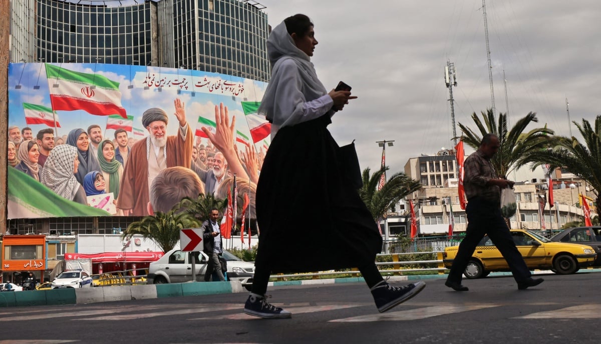 Commuters make their way past a giant billboard of slain Iranian supreme leader Ayatollah Ali Khamenei at the Valiasr Square in Tehran on April 19, 2026. — AFP