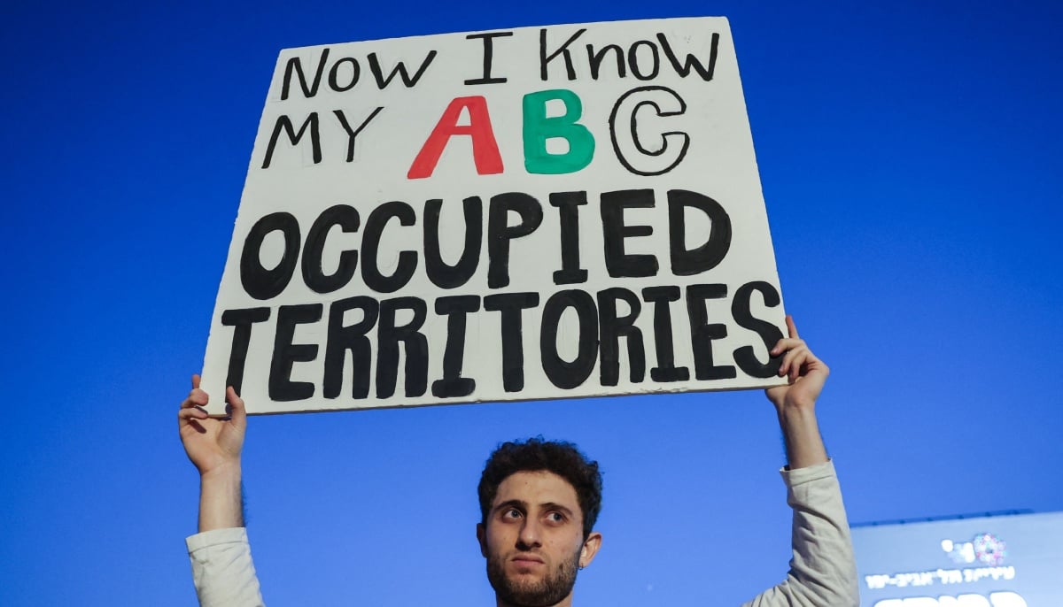 A protester holds up a placard during a demonstration organised by Israeli left-wing activists against the ongoing war with Iran and Lebanon and against the Israeli government, at HaBima Square in Tel Aviv on April 18, 2026. — AFP