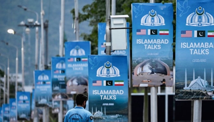 A police personnel walks past posters highlighting Pakistans mediation of Iran-US peace talks, at the Red Zone area in Islamabad, April 18, 2026. — AFP