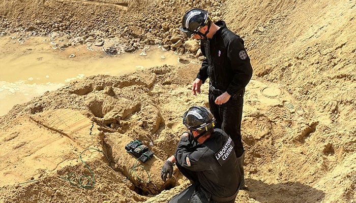 This undated handout photograph made available by the Prefecture de Police on April 19, 2026 shows members of the police Explosive ordnance disposal unit (EOD) operating to neutralise a bomb from World War II partially uncovered near a residential area, in Paris northwestern suburb of Colombes. — AFP