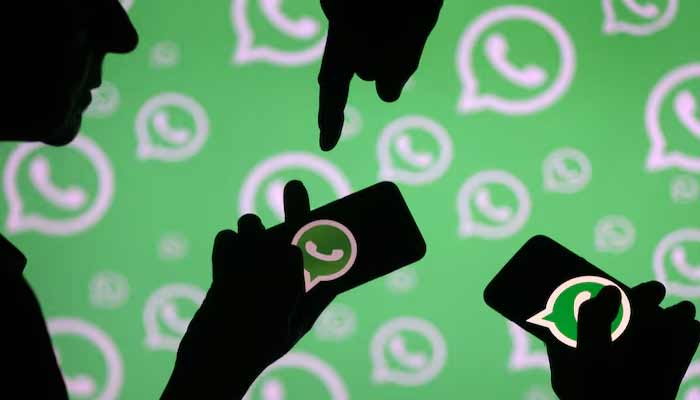 Men pose with smartphones in front of displayed Whatsapp logo in this illustration.— Reuters/File