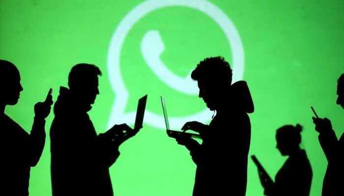 Silhouettes of laptop and mobile device users are seen next to a screen projection of Whatsapp. — Reuters/File