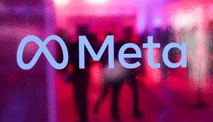 People walk behind a logo of Meta Platforms company, during a conference in Mumbai, India. — Reuters/File