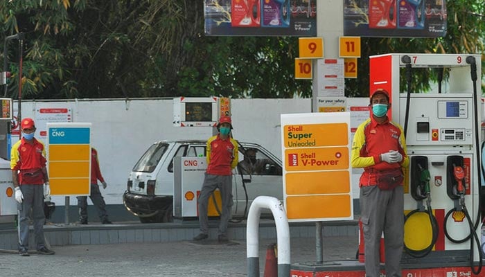 Petrol station workers wait for customers next to petrol pumps in Islamabad, Pakistan, on April 22, 2020. — AFP/File