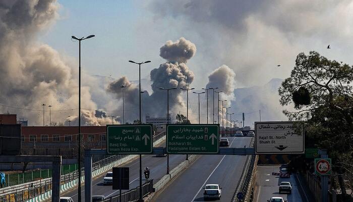Motorists drive along an expressway as plumes of smoke rise after a strike in Tehran on March 5, 2026. — AFP