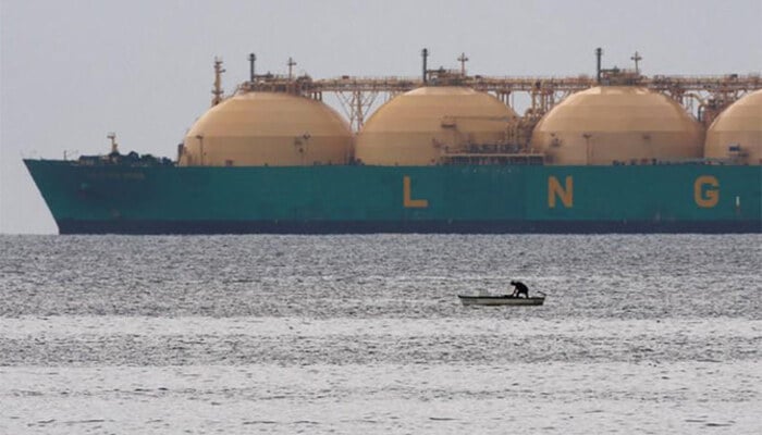 This representational file photo shows a fisherman standing in his boat as a liquid natural gas tanker (LNG) passes the coast near Havana. — Reuters