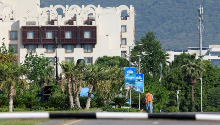 A worker cleans a road at the premises of Convention Centre with Serena hotel in background, as Pakistan prepares to host US and Iran for the second phase of peace talks in Islamabad, April 22, 2026. — Reuters