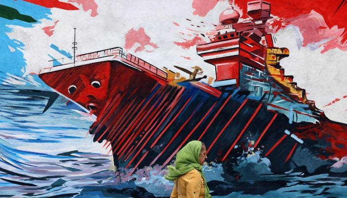 This photo, taken on April 8, 2026, shows a woman walking past an anti-USA and anti-Israel mural in Tehran, Iran. — AFP