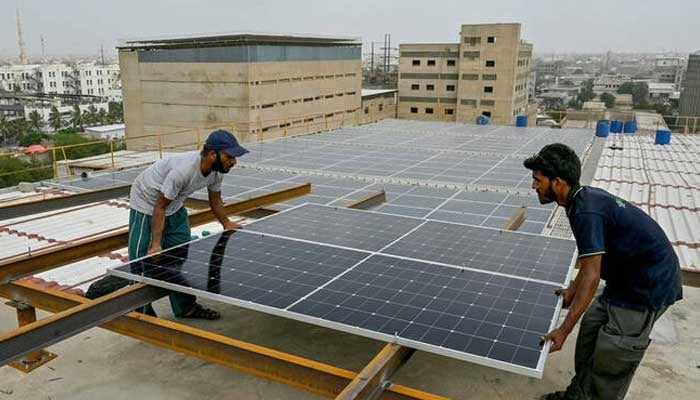 Technicians install solar panels on the rooftop of a factory in Karachi on July 2, 2025. — AFP