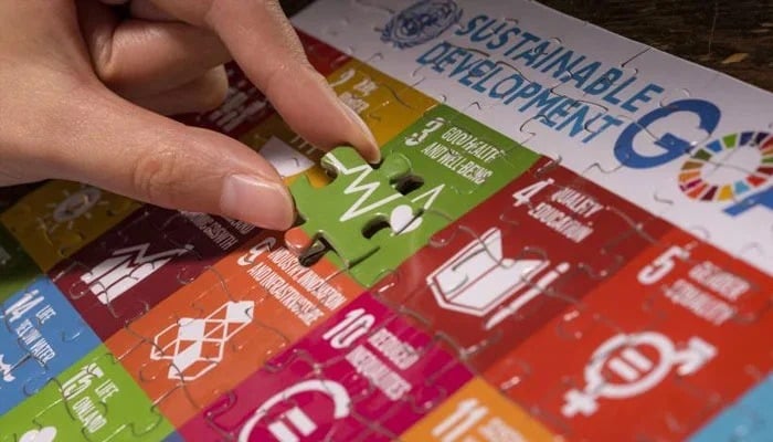 A representational image of a person solving puzzle on SDGs board. — UN website/File