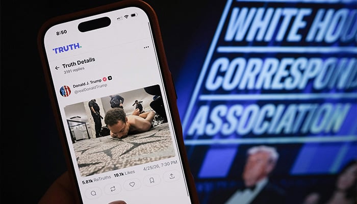 This illustration photo taken in Los Angeles shows a phone with a Truth Social post by US President Donald Trump displaying an image of the alleged suspect in a shooting incident at the White House Correspondents Dinner on the ground after being apprehended on April 25, 2026. — AFP