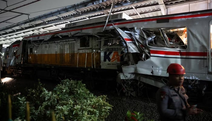 A police officer stands near the damaged train, after two trains collided late on Monday in Bekasi, West Java province, Indonesia, April 28, 2026.— Reuters