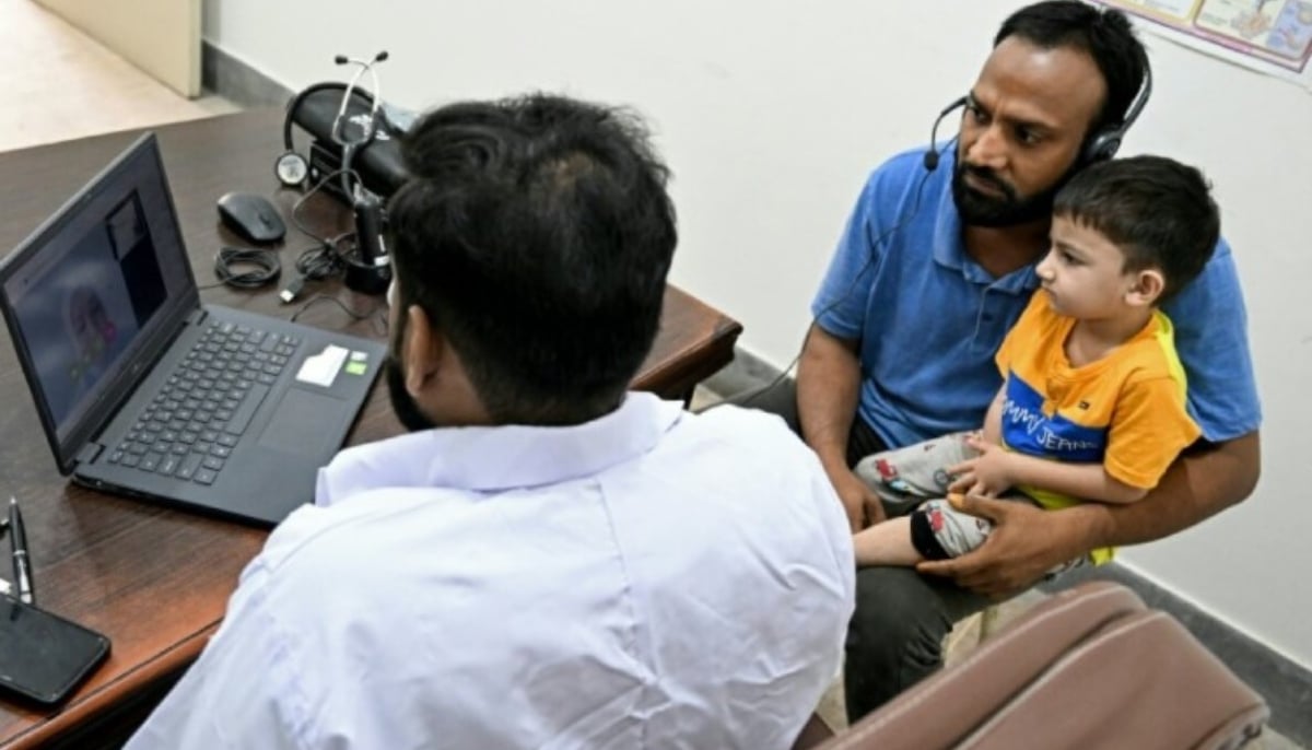 Muhammad Adil (with child) receiving an online and free doctor consultation for his son at a clinic of digital health firm Sehat Kahani in Karachi in this undated image. — AFP
