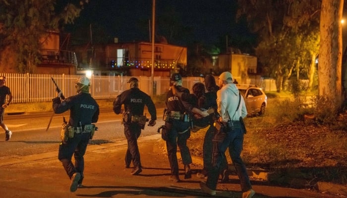 A woman is carried by police during community unrest outside Alice Springs Hospital, where a 47-year-old man arrested in connection with the alleged killing of five-year-old Kumanjayi Little Baby was taken, in Alice Springs, Australia, April 30, 2026. — Reuters