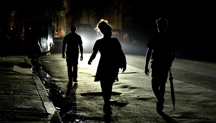 People walk in the street at night as Cuba is hit by an island-wide blackout, in Havana, Cuba, October 18, 2024. — Reuters